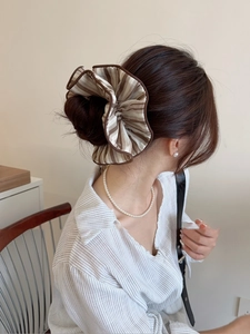 Close-up of oversized striped fabric scrunchie on model with brown and beige patterns