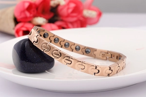 Nahaufnahme von roségoldenem Magnettherapie-Armband mit Germaniumsteinen auf Keramik