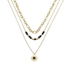 Three-layer gold necklace with black beads and a sun pendant on a plain white background