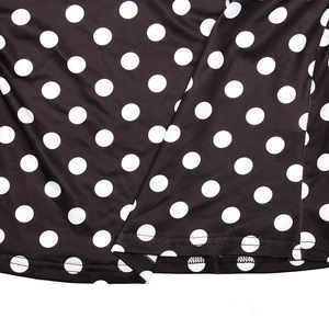 Close-up of black and white polka dot fabric hem with detailed stitching on women's top