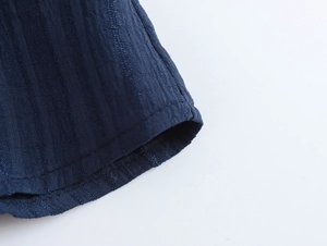 Close-up detail of high-quality stitching and texture on dark blue ruffle shirt sleeve