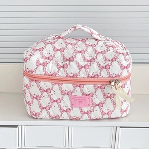 Detailed view of quilted fabric toiletry bag with pink bow pattern and zipper