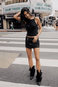 Foto street style di una donna con gonna di jeans nera a vita alta e top all'americana