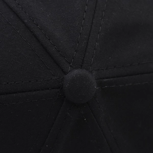 Gros plan détaillé du bouton supérieur et des coutures d'une casquette en coton noir