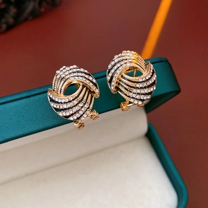 Gros plan sur des boucles d'oreilles dorées en spirale avec émail noir et strass brillants