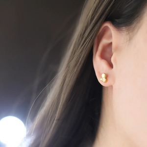 Close-up of a geometric 18K gold-plated honeycomb stud earring with a small center zircon