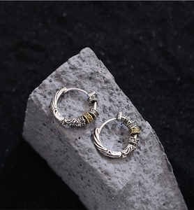 Detail of vintage silver and gold mixed color earrings with intricate relief patterns