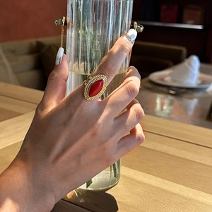 Detail of vintage 18k gold ring with marquise red stone on model holding glassware