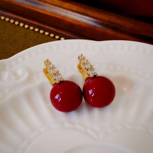 Détail macro de boucles d'oreilles perles rouges dorées avec zircons étincelants