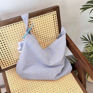 Detail of floral tote bag with blue checks on a vintage rattan chair background