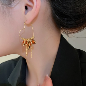 Close-up of 18K gold plated heart earrings with amber crystal drops and long tassels