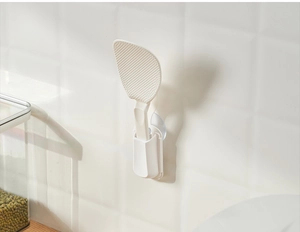 White plastic rice paddle with non-stick texture and suction cup holder on kitchen tile