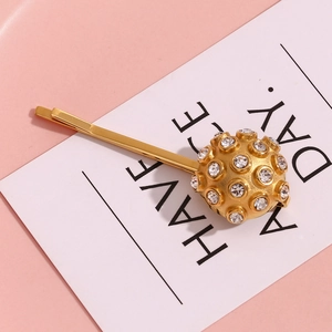 Macro detail of a 18K gold-plated hair clip with a rhinestone-studded spherical ornament