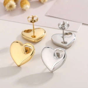 Detailed view of heart-shaped stud earrings in gold and silver finish with hollow design