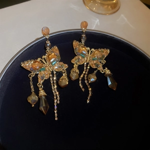 Macro shot of butterfly earrings with champagne crystals and long metallic tassels