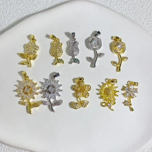Gold and silver flower charms with cubic zirconia and colorful gemstones on stone tray
