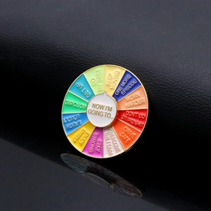 Close-up of a colorful rotating enamel pin with motivational phrases on a black background