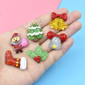 Close-up of resin Christmas charms featuring Santa and trees on a model's palm