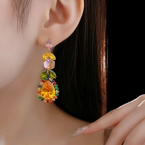 Detailed close-up of leaf-shaped zircon earrings with pink and yellow gems on model