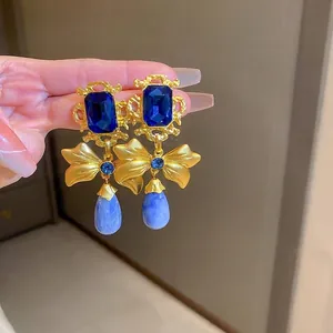 Vintage gold bow earrings with rectangular blue stones and marbled waterdrop pendants