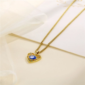 Golden heart necklace with blue evil eye pendant and colorful zircons on beige background