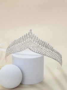 Detailed view of silver crystal bridal crown with sparkling rhinestones on white pedestal