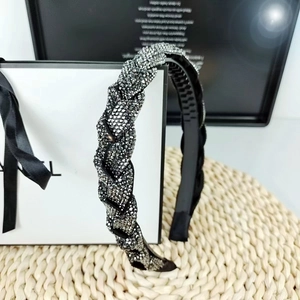 Detailed view of black braided headband with shimmering rhinestones on woven straw mat