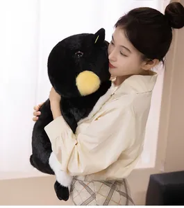 Peluche de manchot empereur géant tenue par une femme pour montrer sa grande taille