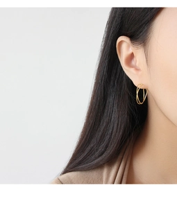 Close-up of minimalist gold interlocking double hoop earrings on model's ear