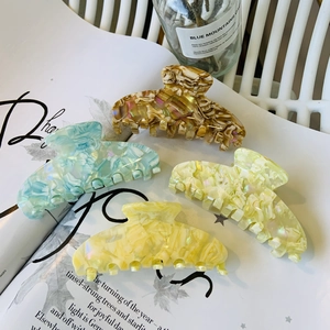Detail view of four colorful acetate hair claws with marble texture on a magazine
