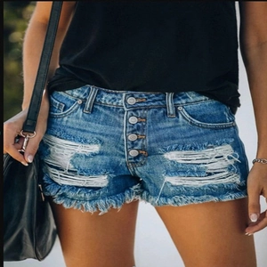 Detail of high waisted blue denim shorts featuring frayed hems and four-button fly closure