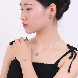 Close-up of a silver daisy jewelry set including necklace, bracelet, and earrings on a model