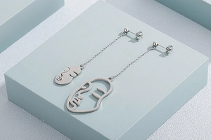 Boucles d'oreilles pendantes asymétriques avec visages abstraits en argent sur bloc bleu