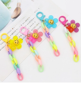 Close-up of four colorful candy-tone smiling flower and bear charms with plastic chains