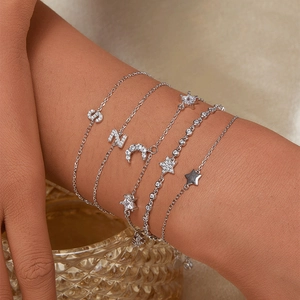 Detailed shot of layered 925 silver bracelets with zircon S and Z letter moon charms