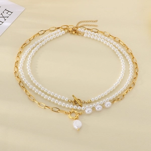 Detail of layered stainless steel necklace with Baroque pearls and golden OT buckle