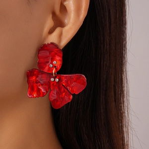 Close-up of red resin flower drop earrings with rhinestone accents on a female model