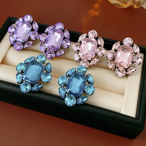 Vue détaillée de trois paires de boucles d'oreilles vintage en cristal violet, rose et bleu