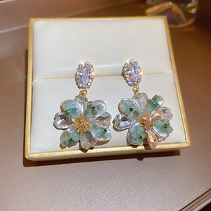 Macro shot of floral earrings with sparkling crystals and pearlescent petals in a box