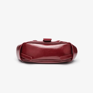 Detail view of the glossy crocodile pattern base on a burgundy patent leather handbag
