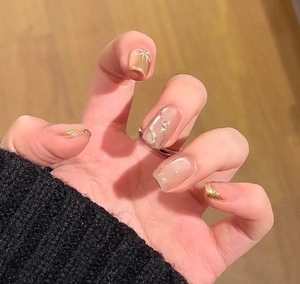 Detail of luxury champagne gold french nails with bow accent and pearl decor on hand