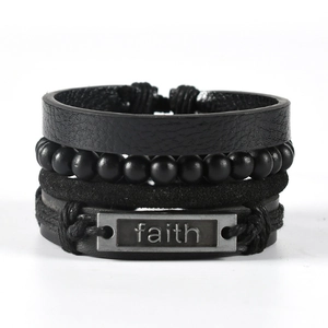 Detail of multi-layer black leather bracelet with beads and metal faith plate