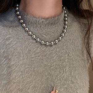 Close-up of minimalist silver pearl necklace on a model wearing a grey sweater