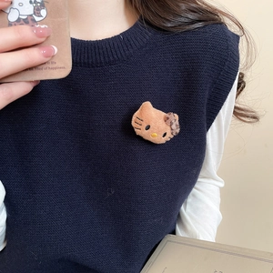 Detail of Hello Kitty flocked brooch with leopard bow on a blue knit sweater vest