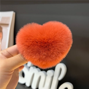 Close-up of bright orange heart-shaped fluffy hair clip with soft faux fur texture
