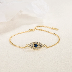 Detailed macro of a gold evil eye bracelet with blue center stone on textured background