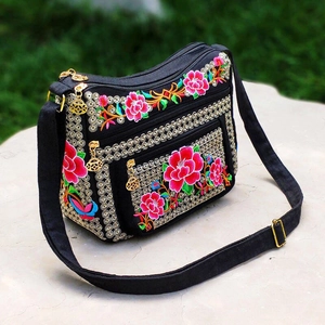 Detail of colorful floral embroidery on a black ethnic shoulder bag with three zipper layers