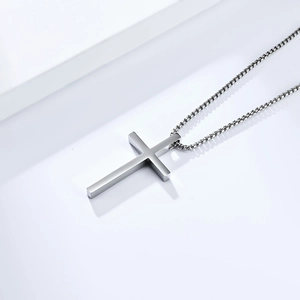 Detailed view of polished silver cross pendant necklace on minimalist geometric background