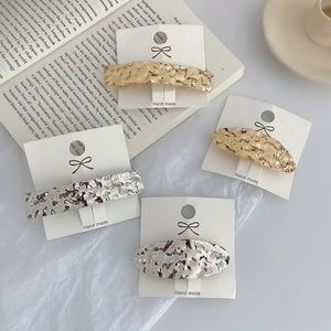 Detailed view of 4 textured metal geometric hair clips in gold and silver on display card
