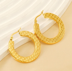 Detailed macro view of large gold hoop earrings with textured star pattern engraving